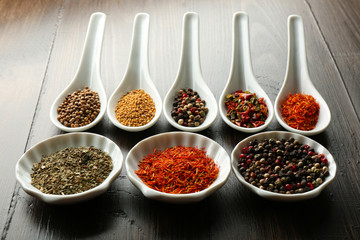Different kinds of spices in bowls and spoons, close-up,