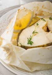 Cod fillets  baked in parchment paper with slices of lemon