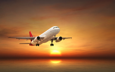 Fototapeta na wymiar Airplane flying above tropical sea at sunset