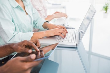 Coworkers using laptop and tablet at desk