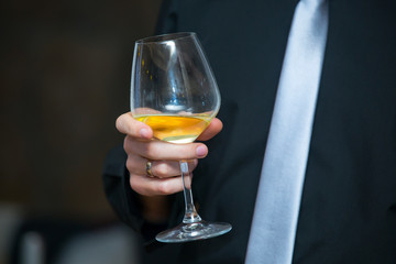 The elegant man in a business suit, holding glass of wine,