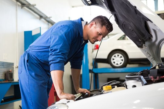 Mechanic Examining Under Hood Of Car