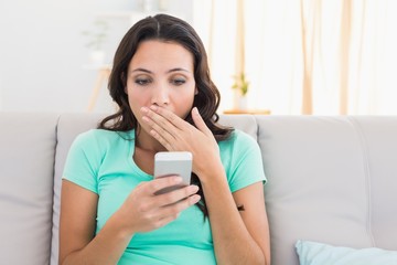 Shocked brunette texting on the phone