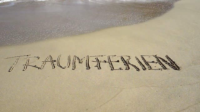 Wort Traumferien in Sand gezeichnet wird von Wellen weggesp&uuml;lt