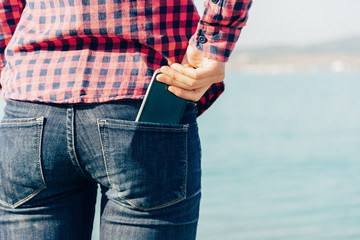 Woman takes out smartphone of her rear pocket of jeans