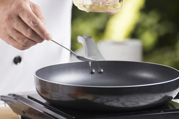 Chef pouring vegetable oil to the pan