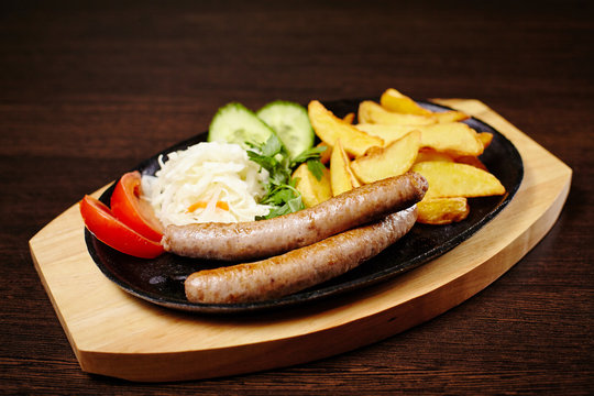 Roasted sausages in a frying pan on wooden table