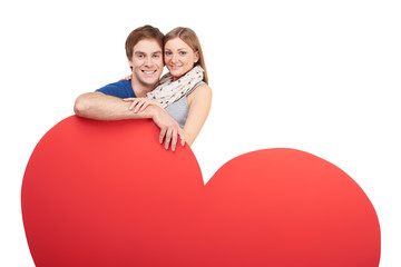Smiling couple hugging behind big heart