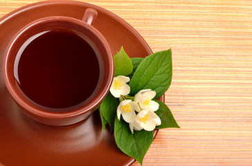 Tea on the ceramic cup with jasmine flower on the wood