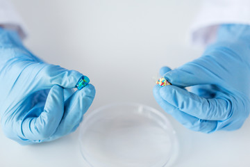 close up of scientist hands holding pill in lab