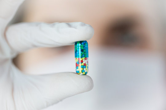 close up of scientist holding pill in lab