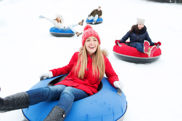 group of happy friends sliding down on snow tubes