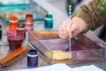 Close up view of marbling proccess, hand with stick