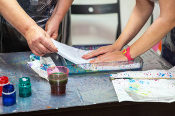 Fototapeta na wymiar People putting silk on water surface for color inks print, ebru