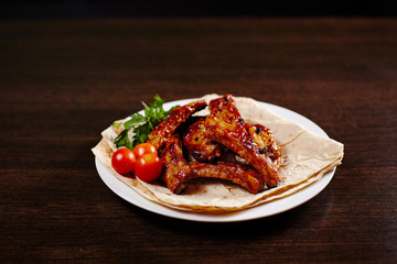 Plate with roasted pork ribs on wooden table