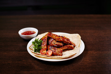 Plate with roasted pork ribs on wooden table