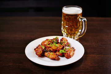 Chicken wings on white dish with beer