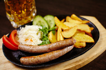 Roasted sausages in a frying pan on wooden table