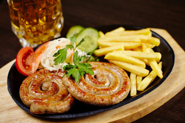 Roasted sausages in a frying pan on wooden table