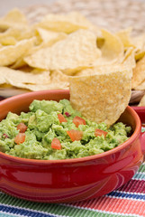 Chunky homemade guacamole in red ceramic dish