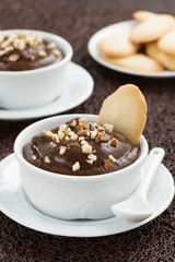chocolate mousse with biscuits in cup on brown background