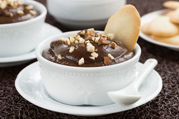 chocolate mousse with biscuits in cup on brown background