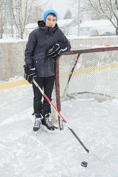 teenager playing hockey outside on a ice rink.