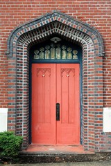 Ornated faded red door set in colorful brick wall
