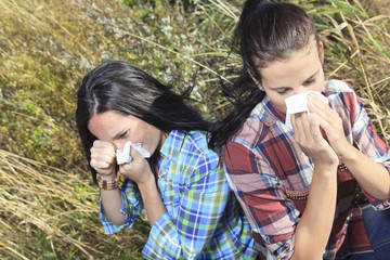 A Young woman sneezing in a field. Concept: seasonal allergy. - obrazy, fototapety, plakaty