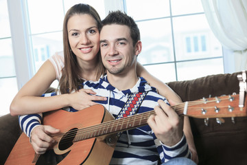 A Handsome man serenading his girlfriend with guitar at home in