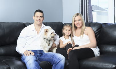 Obraz na płótnie Canvas A Family with pets sit on sofa at home