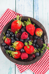 Fresh summer berries fruits in vintage bowl on rustic table