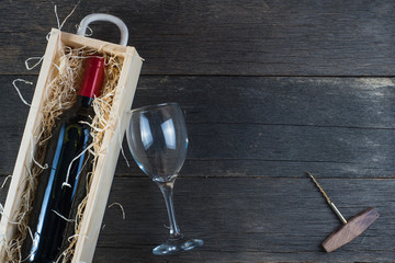 Wooden wine case with red wine on rustic background