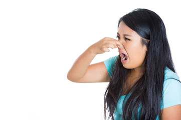 Side profile young woman covers pinches her nose bad smell 