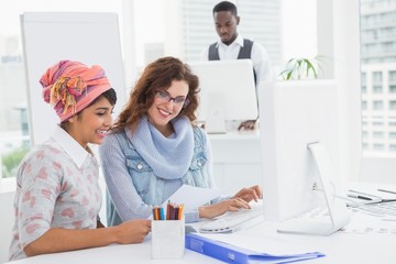 Casual coworkers smiling and suing computer