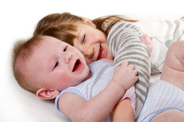 happy little sister hugging her brother lying