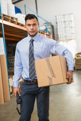 Warehouse manager holding cardboard box and scanner