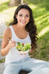 Pretty brunette eating bowl of salad