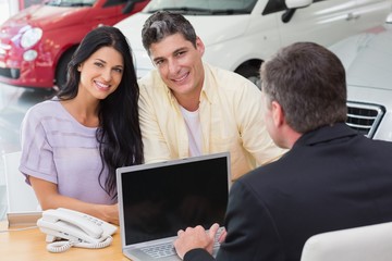 Fototapeta na wymiar Smiling couple buying a new car