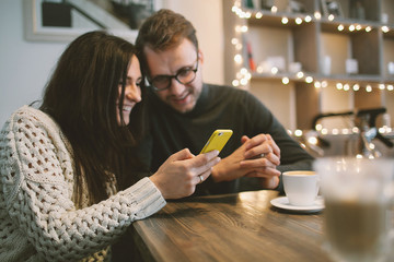 Young couple in cafe sitting with smartphone and coffee