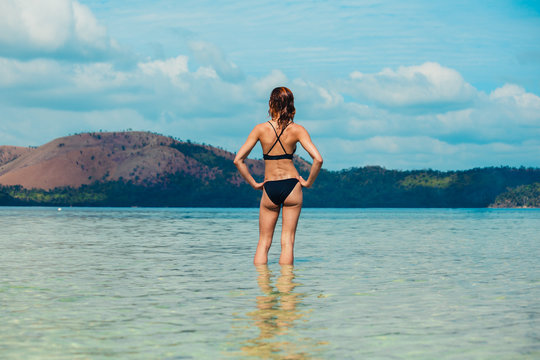 Woman standing in water by tropical beach