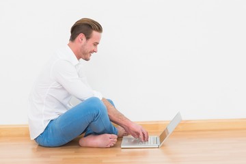 Casual man sitting on floor using laptop