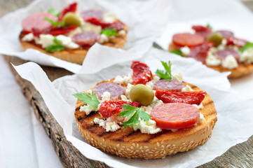 Toasts with dried tomatoes, pepperoni and ricotta