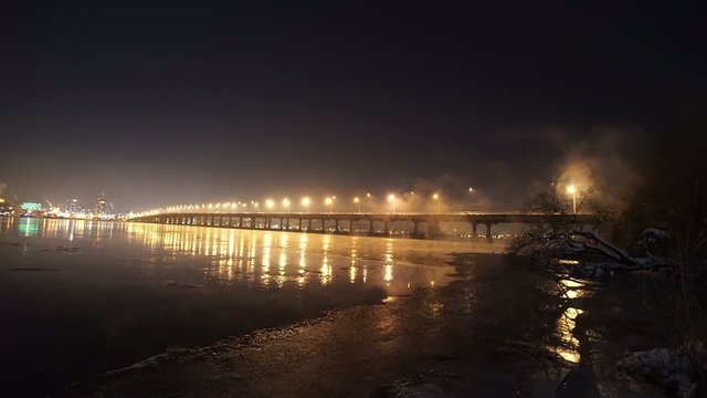 The river with illuminated bridge in winter night