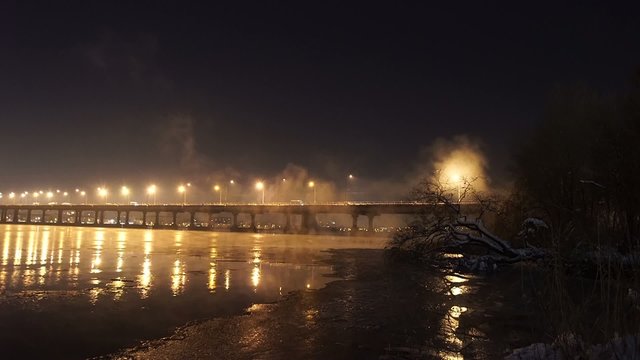 The river with illuminated half-bridge in winter night