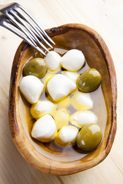 mozzarella cheese in wooden bowl with green olives