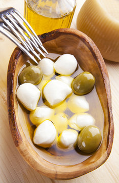 mozzarella cheese in wooden bowl with green olives
