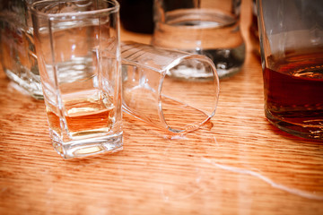 Glass, spilled whiskey and empty bottles on the bar.Alcoholism c