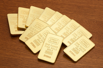 Several one ounce gold bars on wood surface