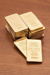One ounce gold bars on dark wood surface